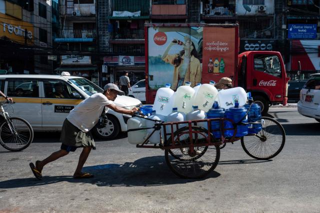 TOPSHOT - A man pushes a cart along a street in Yangon on December 23, 2025. (Photo by Sai Aung MAIN / AFP)
