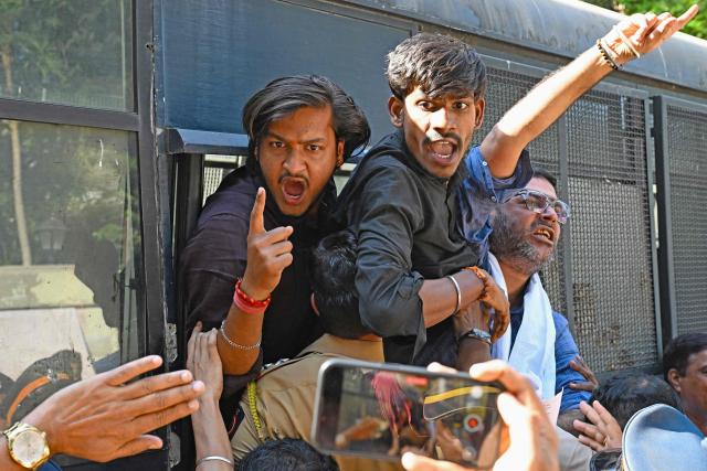 Detained Vishva Hindu Parishad (VHP) activists shout slogans from a police vehicle during a protest near the Bangladesh Deputy High Commission in Mumbai on December 23, 2025 held to condemn the killing of Hindu garment worker Dipu Chandra Das. On December 18, angry mobs in the majority Muslim nation of Bangladesh's capital of Dhaka attacked the offices of Prothom Alo and the Daily Star, torching parts of the buildings and vandalising the premises of the two publications caught up in surging anti-India sentiment in the wake of popular student leader Sharif Osman Hadi's death. The violence also saw Hindu garment worker Das killed following allegations of blasphemy. (Photo by Indranil MUKHERJEE / AFP)