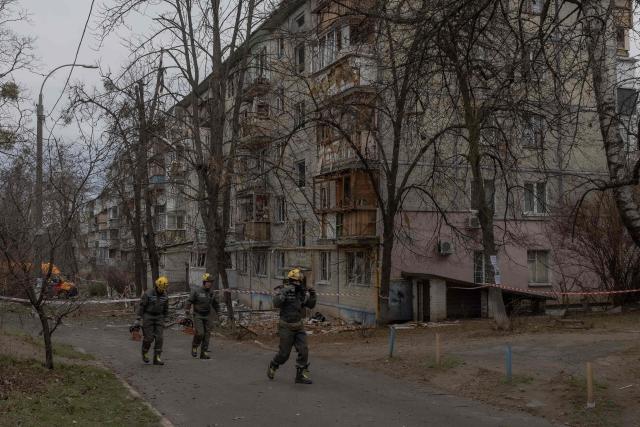 Ukrainian rescuers walk next to a heavily damaged residential building following a drone strike in Kyiv, on December 23, 2025, amid the Russian invasion of Ukraine. Several Ukrainian regions suffered power cuts in frigid winter weather on December 23, 2025, after Russia launched its latest deadly large-scale attack with drones and missiles, authorities said. (Photo by Roman PILIPEY / AFP)