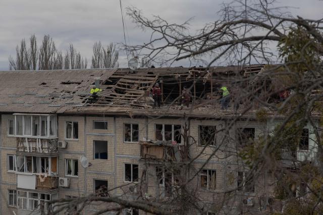 Workers clear debris from the roof of a heavily damaged residential building following a drone strike in Kyiv, on December 23, 2025, amid the Russian invasion of Ukraine. Several Ukrainian regions suffered power cuts in frigid winter weather on December 23, 2025, after Russia launched its latest deadly large-scale attack with drones and missiles, authorities said. (Photo by Roman PILIPEY / AFP)