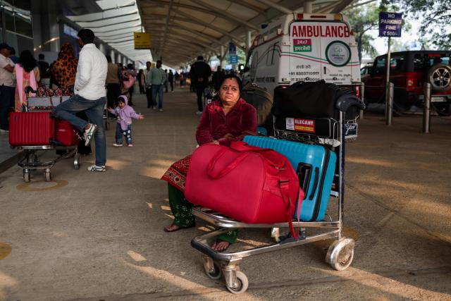 Stranded passengers wait near airline ticketing desks amid flight cancellations and delays owing to dense fog at the Lal Bahadur Shastri International Airport in Varanasi on December 23, 2025. (Photo by Niharika KULKARNI / AFP)