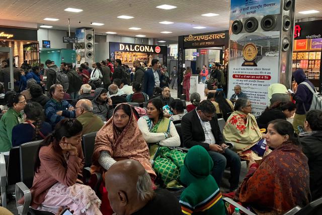 Stranded passengers wait amid flight cancellations and delays owing to dense fog at the Lal Bahadur Shastri International Airport in Varanasi on December 23, 2025. (Photo by Niharika KULKARNI / AFP)