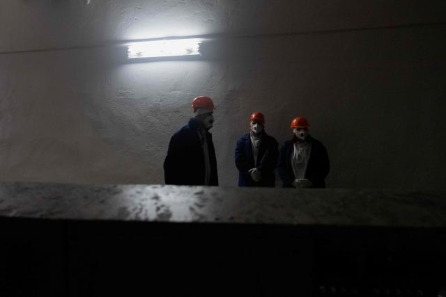 Workers stand in one of the rooms of the Chernobyl Nuclear Power Plant, in Chernobyl, on December 22, 2025, amid the Russian invasion of Ukraine. The Chernobyl Nuclear Power Plant director said on December 23, 2025, fully restoring the internal radiation shelter could take three to four years, after a hit earlier this year punched a hole in the outer radiation shell, triggering a warning from the International Atomic Energy Agency (IAEA) that it had "lost its primary safety functions." And warned that another Russian hit could see the inner shell collapse. (Photo by Tetiana DZHAFAROVA / AFP)