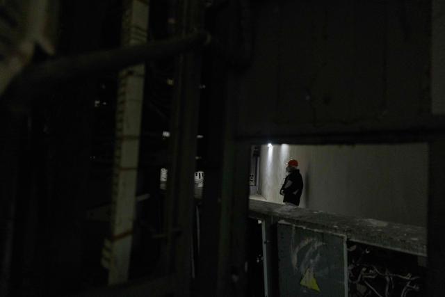 A worker stands in one of the buildings of the Chernobyl Nuclear Power Plant, in Chernobyl, on December 22, 2025, amid the Russian invasion of Ukraine. The Chernobyl Nuclear Power Plant director said on December 23, 2025, fully restoring the internal radiation shelter could take three to four years, after a hit earlier this year punched a hole in the outer radiation shell, triggering a warning from the International Atomic Energy Agency (IAEA) that it had "lost its primary safety functions." And warned that another Russian hit could see the inner shell collapse. (Photo by Tetiana DZHAFAROVA / AFP)