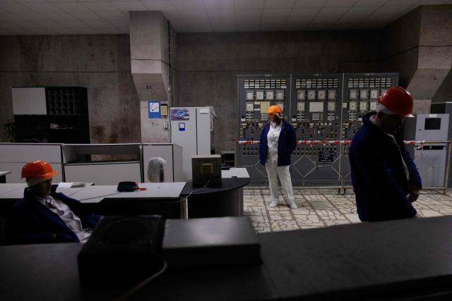 Employees stand at the control panel of the third power unit in Chernobyl Nuclear Power Plant, in Chernobyl, on December 22, 2025, amid the Russian invasion of Ukraine. The Chernobyl Nuclear Power Plant director said on December 23, 2025, fully restoring the internal radiation shelter could take three to four years, after a hit earlier this year punched a hole in the outer radiation shell, triggering a warning from the International Atomic Energy Agency (IAEA) that it had "lost its primary safety functions." And warned that another Russian hit could see the inner shell collapse. (Photo by Tetiana DZHAFAROVA / AFP)