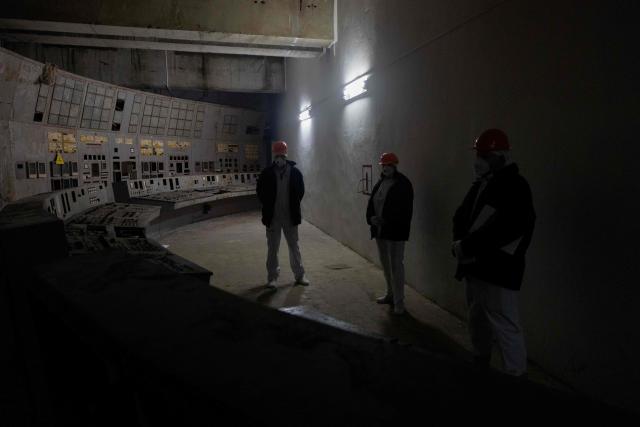 Employees stand at the control panel of the fourth power unit in Chernobyl Nuclear Power Plant, in Chernobyl, on December 22, 2025, amid the Russian invasion of Ukraine. The Chernobyl Nuclear Power Plant director said on December 23, 2025, fully restoring the internal radiation shelter could take three to four years, after a hit earlier this year punched a hole in the outer radiation shell, triggering a warning from the International Atomic Energy Agency (IAEA) that it had "lost its primary safety functions." And warned that another Russian hit could see the inner shell collapse. (Photo by Tetiana DZHAFAROVA / AFP)