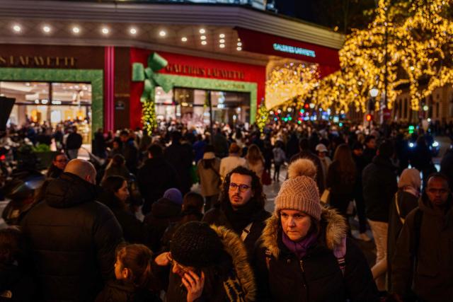 Shoppers walk by the Galeries Lafayette department store ahead of Christmas celebrations in central Paris on December 23, 2025. (Photo by Dimitar DILKOFF / AFP)