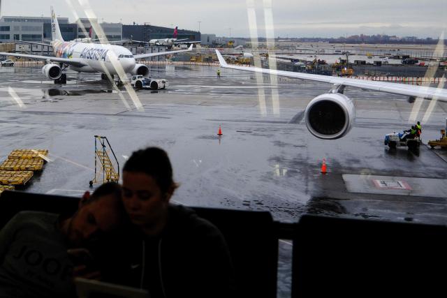 Passengers wait to board a flight at JFK International Airport in New York on December 23, 2025. (Photo by CHARLY TRIBALLEAU / AFP)