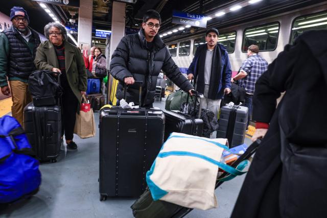 Travelers make their way to board a train at Penn Station on December 23, 2025 in New York. (Photo by kena betancur / AFP)