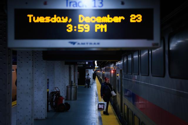 Travelers board a train at Penn Station on December 23, 2025 in New York. (Photo by kena betancur / AFP)