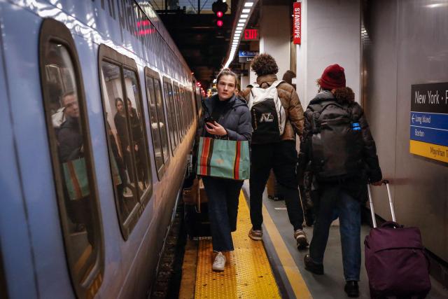 Travelers board a train at Penn Station on December 23, 2025 in New York. (Photo by kena betancur / AFP)