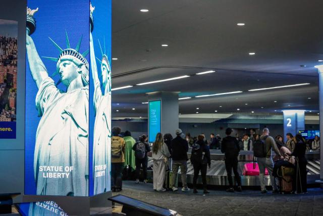 Passengers wait by the baggage carousel after arriving to La Guardia Airport on December 23, 2025 in New York. (Photo by kena betancur / AFP)