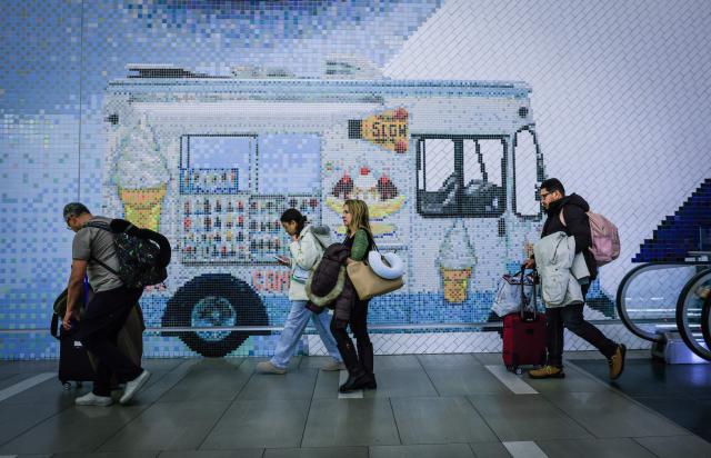 Travelers walk through the arrival hall after arriving to La Guardia Airport on December 23, 2025 in New York. (Photo by kena betancur / AFP)