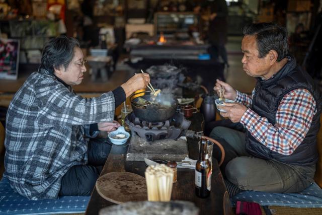 This picture taken on December 12, 2025 shows people eating bear meat hot pot at a restaurant in Chichibu, Saitama prefecture. Since Japan recorded a spike in deadly bear attacks, Koji Suzuki has struggled to keep up with booming demand for grilled cuts of the animal at his restaurant. Cooked on a stone slate -- or in hot pot with vegetables -- the meat comes from bears culled to curb maulings that have killed a record 13 people this year. (Photo by Yuichi YAMAZAKI / AFP) / To go with 'JAPAN-ENVIRONMENT-BEAR-FOOD' by Kyoko Hasegawa and Hiroshi Hiyama in Sapporo