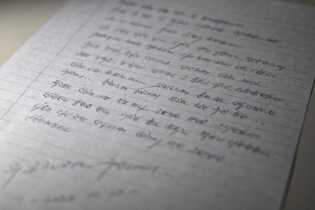 This photo illustration taken in Seoul on December 24, 2025 shows a copy of a letter written on October 28, 2025 by North Korean prisoners of war in Ukraine. Two North Korean prisoners of war held by Ukraine have expressed their desire to start a "new life" in South Korea, according to a letter seen by AFP on December 24. (Photo by Jung Yeon-je / AFP)
