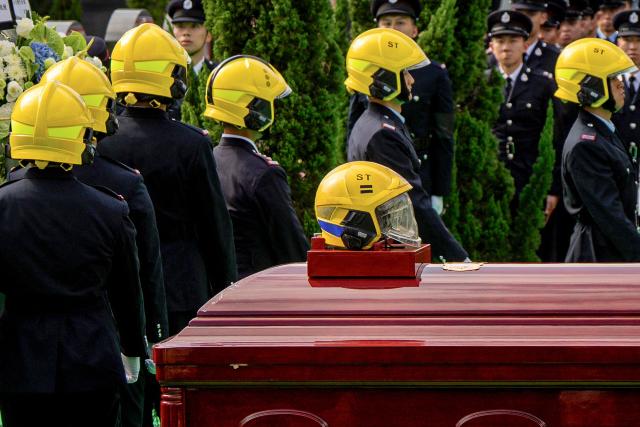 (FILES) Mourners attend the burial of firefighter Ho Wai-ho, who died in the deadly November 26 fire at the Wang Fuk Court residential estate in Tai Po district, at Gallant Garden in Hong Kong, on December 19, 2025. Thousands are grieving the 161 killed at Wang Fuk Court, a disaster few could imagine happening in one of Asia's safest and most developed cities. Even as the Hong Kong government forges ahead with investigations and relief efforts, experts caution that the psychological scars will be hard to heal for survivors, bereaved families and onlookers alike. (Photo by Leung Man Hei / AFP)