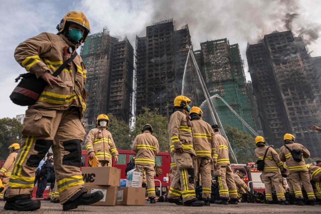 (FILES) Firemen get ready after a major fire swept through several apartment blocks at the Wang Fuk Court residential estate in Hong Kong's Tai Po district on November 27, 2025. Thousands are grieving the 161 killed at Wang Fuk Court, a disaster few could imagine happening in one of Asia's safest and most developed cities. Even as the Hong Kong government forges ahead with investigations and relief efforts, experts caution that the psychological scars will be hard to heal for survivors, bereaved families and onlookers alike. (Photo by Dale DE LA REY / AFP)