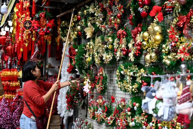 A seller arranges Christmas decorations at her shop in Hanoi on December 24, 2025. (Photo by Nhac NGUYEN / AFP)
