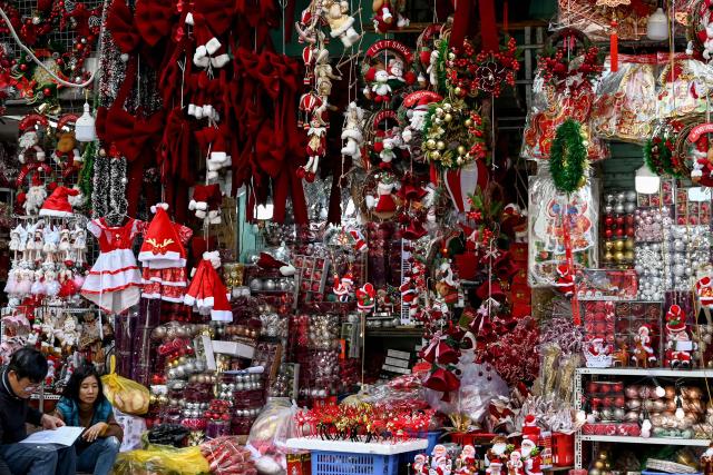 Sellers sit in front of their shop selling Christmas decorations in Hanoi on December 24, 2025. (Photo by Nhac NGUYEN / AFP)