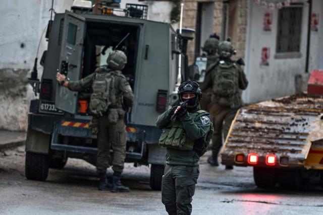 Israeli security forces secure a street as they leave the Palestinian village of Bizariya, in the occupied West Bank, where Israeli authorities demolished the house of a Palestinian man killed in July after he and another man reportedly killed an Israeli settler on the same day, on December 24, 2025. (Photo by Zain JAAFAR / AFP)