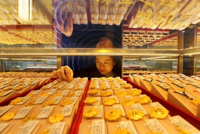 TOPSHOT - A saleswoman adjusts gold jewellery for sale at a shop in Lianyungang, in China’s eastern Jiangsu province on December 24, 2025. (Photo by AFP) / China OUT