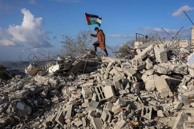 A boy poses for photos taken by his parents on the rubble of a house demolished by Israeli authorities in the Palestinian village of Bizariya, in the Israeli-occupied West Bank, on December 24, 2025. The home belonged to a Palestinian man who was killed in July after he and another man reportedly killed an Israeli settler on the same day. (Photo by Zain JAAFAR / AFP)