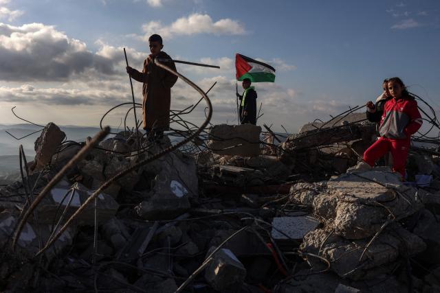 Children pose for photos taken by their parents on the rubble of a house demolished by Israeli authorities in the Palestinian village of Bizariya, in the Israeli-occupied West Bank, on December 24, 2025. The home belonged to a Palestinian man who was killed in July after he and another man reportedly killed an Israeli settler on the same day. (Photo by Zain JAAFAR / AFP)