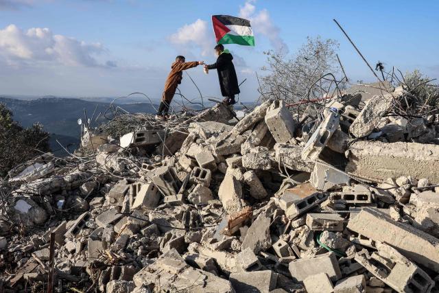 Children pose for photos taken by their parents on the rubble of a house demolished by Israeli authorities in the Palestinian village of Bizariya, in the Israeli-occupied West Bank, on December 24, 2025. The home belonged to a Palestinian man who was killed in July after he and another man reportedly killed an Israeli settler on the same day. (Photo by Zain JAAFAR / AFP)