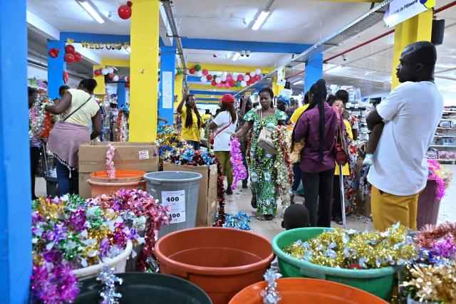 People buy decorative garlands in a toy and variety store for Christmas celebrations in Abidjan on December 23, 2025. (Photo by Sia KAMBOU / AFP)