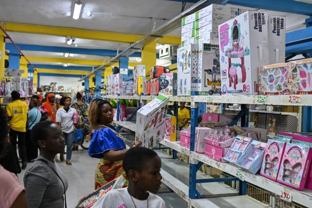 Customers buy children's toys as Christmas gifts in a store selling toys and other decorations for Christmas celebrations in Abidjan on December 23, 2025. (Photo by Sia KAMBOU / AFP)