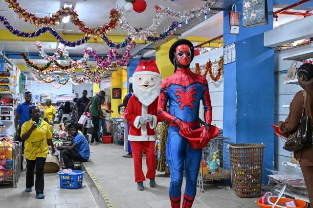 Customers watch a man dressed as Santa Claus in a store selling toys and other decorations for Christmas celebrations in Abidjan on December 23, 2025. (Photo by Sia KAMBOU / AFP)