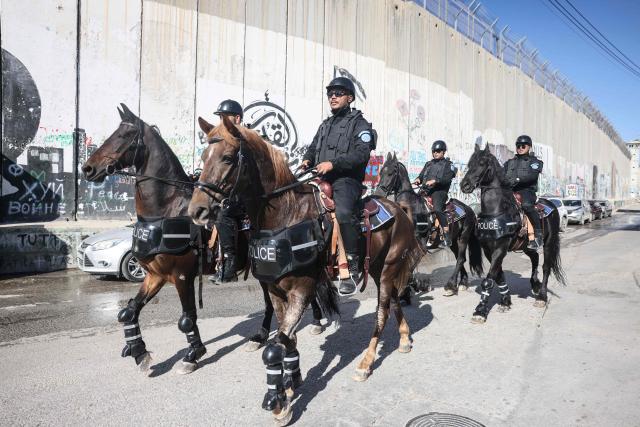 Palestinian mounted police wait for the arrival of the Latin Patriarch of Jerusalem, Cardinal Pierbattista Pizzaballa, along the controversial separation barrier in Bethlehem, in the Israeli-occupied West Bank, before the annual Christmas Eve procession at the Church of the Nativity on December 24, 2025. (Photo by AHMAD GHARABLI / AFP)
