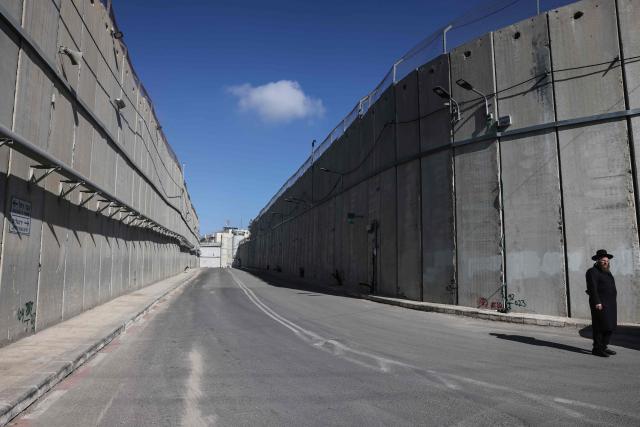 An ultra-Orthodox Jewish man stands at Israel's "checkpoint 300" along the controversial separation barrier near Bethlehem, in the Israeli-occupied West Bank, on December 24, 2025. (Photo by AHMAD GHARABLI / AFP)