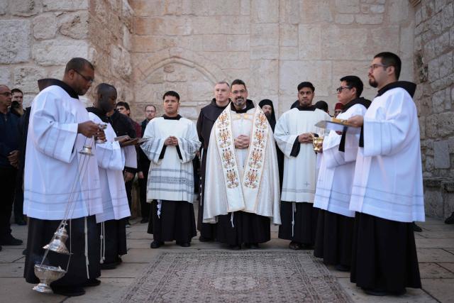 Clergymen and alter boys wait ahead of Christmas service in the Manger Square outside the Church of the Nativity (R) in the biblical city of Bethlehem in the occupied West Bank on Christmas eve on December 24, 2025. Scouts marched under a clear blue sky in Bethlehem on December 24, 2025, as the Palestinian city emerged from the shadow of the war in Gaza to celebrate its first festive Christmas in more than two years. Throughout the Gaza war that began with Hamas's attack on Israel in October 2023, a sombre tone marked Chistmases in Bethlehem, the biblical birthplace of Jesus Christ. (Photo by ilia yefimovich / AFP)