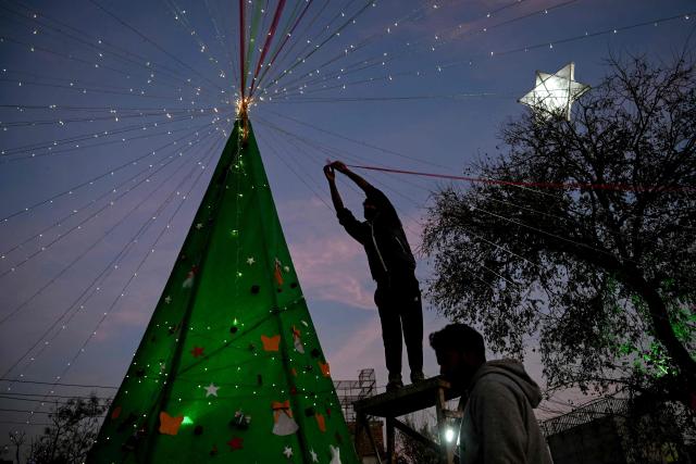 A man decorates a Christmas tree during celebrations on Christmas Eve in Islamabad on December 24, 2025. (Photo by Farooq NAEEM / AFP)