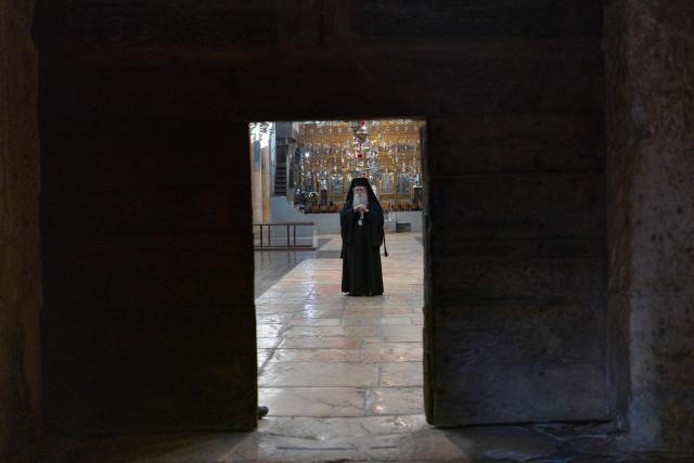Orthodox Christian priests stands in the Church of the Nativity, ahead of the arrival of Latin Patriarch of Jerusalem to celebrate Christmas Mass, in the biblical city of Bethlehem in the Israeli-occupied West Bank on Christmas eve on December 24, 2025. Scouts marched under a clear blue sky in Bethlehem on December 24, 2025, as the Palestinian city emerged from the shadow of the war in Gaza to celebrate its first festive Christmas in more than two years. Throughout the Gaza war that began with Hamas's attack on Israel in October 2023, a sombre tone marked Chistmases in Bethlehem, the biblical birthplace of Jesus Christ. (Photo by ILIA YEFIMOVICH / AFP)