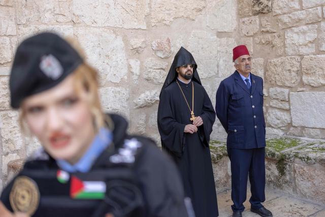 An Armenian priest waits outside the Church of the Nativity  ahead of the arrival of Latin Patriarch of Jerusalem for Christmas eve celebrations in the biblical West Bank city of Bethlehem, believed to be the birthplace of Jesus Christ, on December 24, 2025. Scouts marched under a clear blue sky in Bethlehem on December 24, 2025, as the Palestinian city emerged from the shadow of the war in Gaza to celebrate its first festive Christmas in more than two years. Throughout the Gaza war that began with Hamas's attack on Israel in October 2023, a sombre tone marked Chistmases in Bethlehem, the biblical birthplace of Jesus Christ. (Photo by ILIA YEFIMOVICH / AFP)