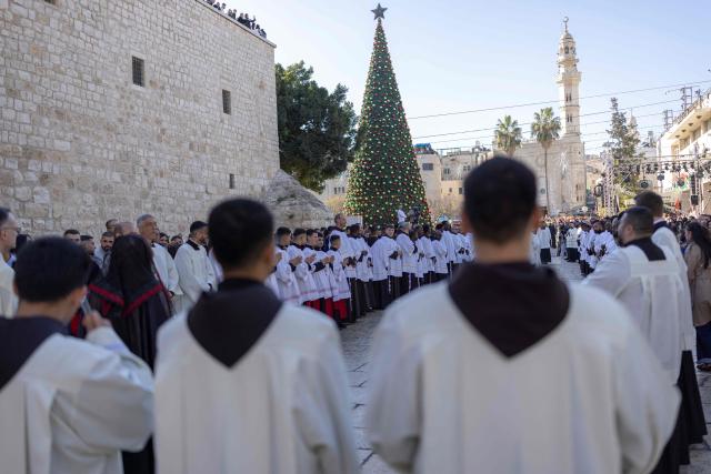 Members of the clergy take part in the yearly Christmas procession led by Latin Patriarch of Jerusalem outside the Church of the Nativity in the Israeli-occupied West Bank city of Bethlehem  on December 24, 2025. Scouts marched under a clear blue sky in Bethlehem on December 24, 2025, as the Palestinian city emerged from the shadow of the war in Gaza to celebrate its first festive Christmas in more than two years. Throughout the Gaza war that began with Hamas's attack on Israel in October 2023, a sombre tone marked Chistmases in Bethlehem, the biblical birthplace of Jesus Christ. (Photo by ilia yefimovich / AFP)