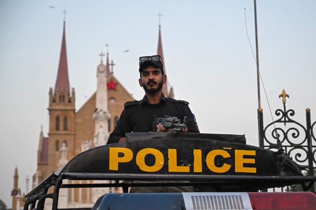 A police personnel stands guard outside the Saint Patrick's Cathedral on Christmas Eve in Karachi on December 24, 2025. (Photo by Rizwan TABASSUM / AFP)