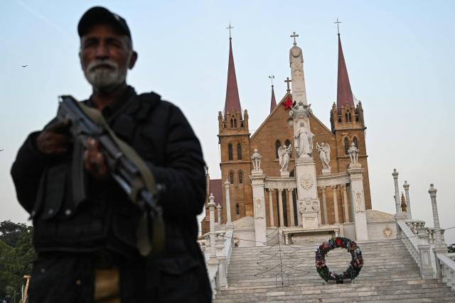 A police personnel stands guard outside the Saint Patrick's Cathedral on Christmas Eve in Karachi on December 24, 2025. (Photo by Rizwan TABASSUM / AFP)