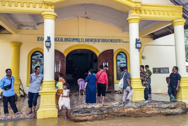 Batak Christian Protestant Church (HKBP) members arrive from evacuation shelters to attend a Christmas Eve mass at a flood-ravaged church in the Hutanabolon village of Central Tapanuli, North Sumatra on December 24, 2025. (Photo by Damai Mendrofa / AFP)