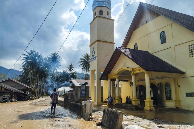 TOPSHOT - Batak Christian Protestant Church (HKBP) members arrive from evacuation shelters to attend a Christmas Eve mass at a flood-ravaged church in the Hutanabolon village of Central Tapanuli, North Sumatra on December 24, 2025. (Photo by Damai Mendrofa / AFP)