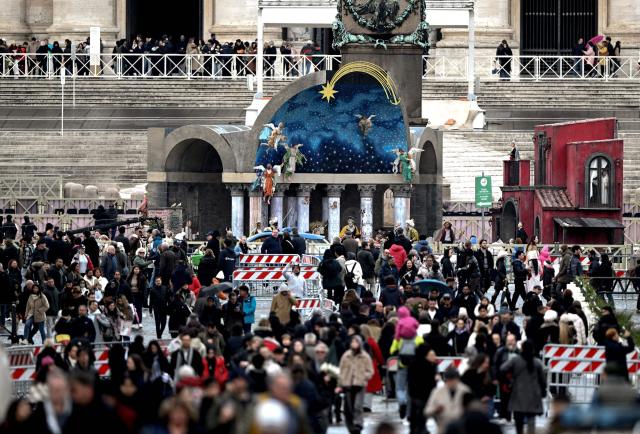 Pedestrians walk past the nativity scene in St. Peter's square at the Vatican on Christmas Eve on December 24, 2025. (Photo by TIZIANA FABI / AFP)