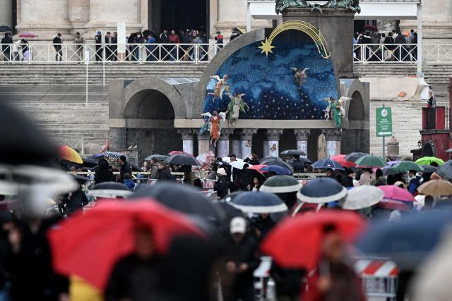 Pedestrians walk past the nativity scene in St. Peter's square at the Vatican on Christmas Eve on December 24, 2025. (Photo by TIZIANA FABI / AFP)