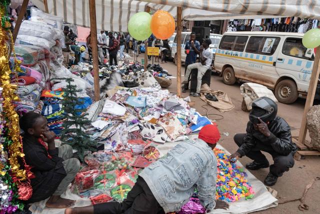 Vendors display Christmas merchandise and other goods as they wait for customers along a busy commercial street in Kampala on December 24, 2025, on Christmas eve. (Photo by Badru KATUMBA / AFP)