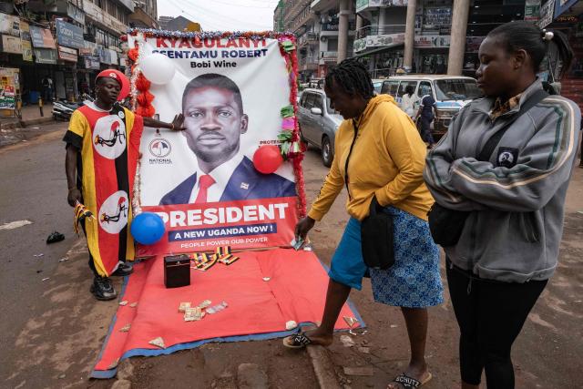 A woman donates money to a National Unity Platform presidential candidate Bobi Wine, whose real name is Robert Kyagulanyi, supporter in Kampala on December 24, 2025 on Christmas eve. (Photo by Badru KATUMBA / AFP)