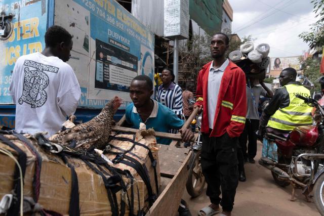 Passengers carry goods purchased while waiting for taxis to travel to their villages in Kampala on December 24, 2025 on Christmas eve. (Photo by Badru KATUMBA / AFP)