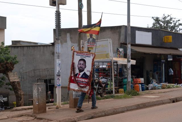 A National Unity Platform presidential candidate Bobi Wine, whose real name is Robert Kyagulanyi, supporter carries a poster bearing his face in Kampala on December 24, 2025 on Christmas eve. (Photo by Badru KATUMBA / AFP)