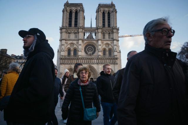 Visitors walk past the Notre Dame Cathedral in central Paris on Christmas eve, December 24, 2025. (Photo by Dimitar DILKOFF / AFP)