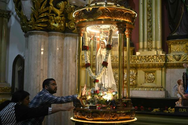 Christian devotees offer prayers before an idol of Mother Mary on the eve of Christmas celebrations at St. Mary’s Basilica in Bengaluru on December 24, 2025. (Photo by Idrees MOHAMMED / AFP)